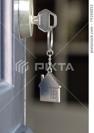 Open door to a new home with key and home shaped keychain. Mortgage, investment, real estate, property and new home concept 74168852