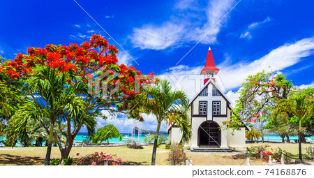 Scenery of beautiful Mauritius island - Red church on the beach with blooming flamboyant tree. 74168876
