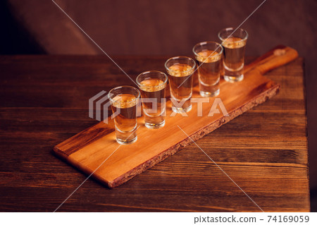 Variation of hard alcoholic shots served on bar counter. Blur bottles on background. Variation of hard alcoholic shots served on bar counter. Blur bottles on background. 74169059