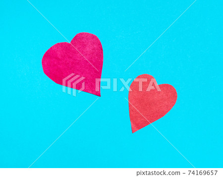 two different hearts cut from red papers on blue 74169657