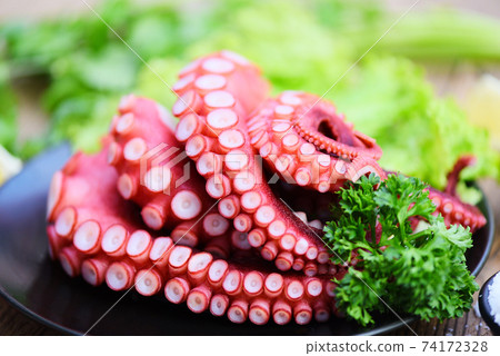 Fresh octopus food on black plate, cooked squid salad vegetable seafood cuttlefish dinner restaurant, Boiled octopus tentacles. 74172328