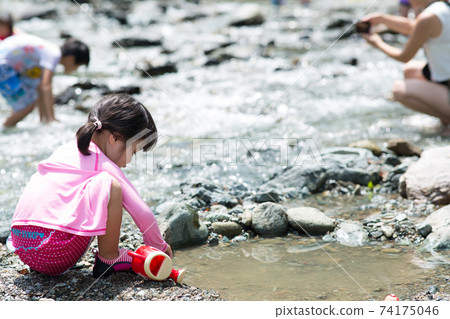 Girl playing on the riverbank Girl playing on the riverbank 74175046