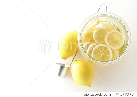 Photographed undiluted solution of lemon squash and lemonade in a storage bottle, ladle and lemon on a white background (overhead view) 74177376