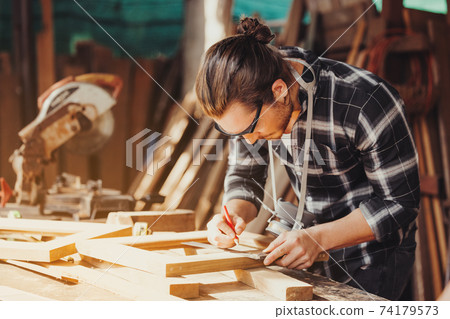 Confident wood worker expert. Young man working at factory. Skilled carpenter 74179573