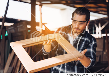 Confident wood worker expert. Young man working at factory. Skilled carpenter 74179576
