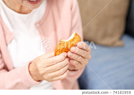 Senior woman eating rice crackers 74181959