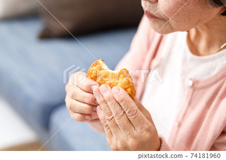Senior woman eating rice crackers 74181960