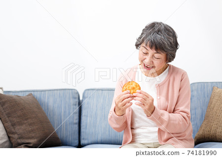 Senior woman eating rice crackers Senior woman eating rice crackers 74181990