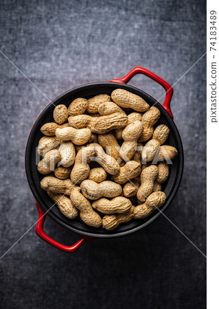 Roasted peanuts. Tasty groundnuts in pot. 74183489