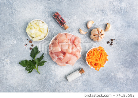 Raw ingredients for cooking a roast. Chicken fillet, grated carrots and chopped onion garlic with herbs and spices. gray background, copy space, top view. Raw ingredients for cooking a roast. Chicken fillet, grated carrots and chopped onion garlic with herbs and spices. gray background, copy space, top view. 74183592