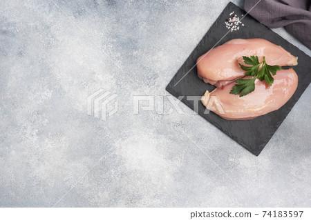 Raw chicken breast fillet, raw chicken meat on a black stand, gray background. 74183597