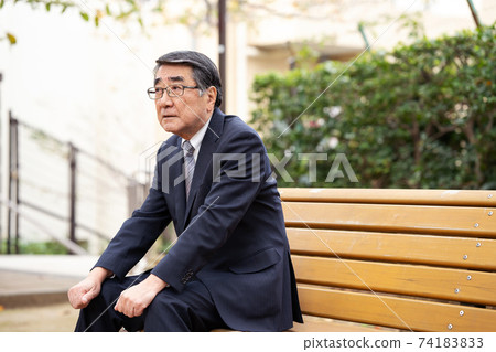 A businessman twilight on a park bench A businessman twilight on a park bench 74183833