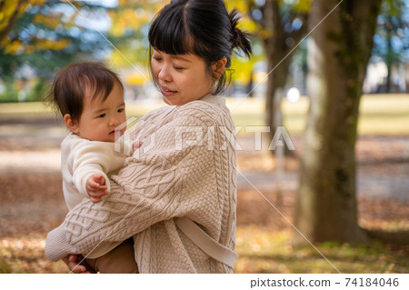 Baby playing with mom in autumn park (moody) 74184046