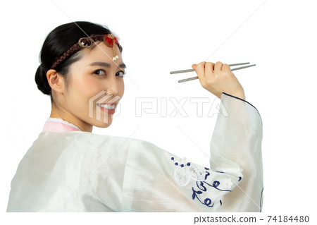 Young beautiful woman holding asian chopsticks with big smile. Beautiful young woman with perfect smile tooth. Isolated on white. asian girl dressing in traditional Hanbok style portrait Young beautiful woman holding asian chopsticks with big smile. Beautiful young woman with perfect smile tooth. Isolated on white. asian girl dressing in traditional Hanbok style portrait 74184480
