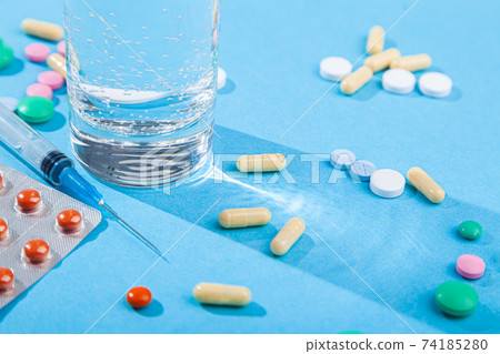 Colorful scattered tablets, water glass, blister with medical pills, multivitamins 74185280