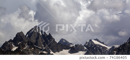 Panoramic view on high snowy mountains with glacier and cloudy sky before rain Panoramic view on high snowy mountains with glacier and cloudy sky before rain 74186405