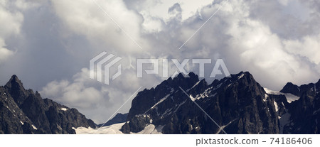 Panoramic view on high mountains with snow and glacier in clouds before rain Panoramic view on high mountains with snow and glacier in clouds before rain 74186406