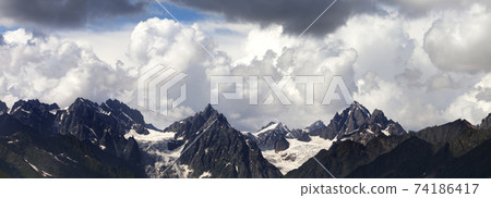 Panoramic view on high summer mountains with snow and glacier and cloudy sunlit sky Panoramic view on high summer mountains with snow and glacier and cloudy sunlit sky 74186417