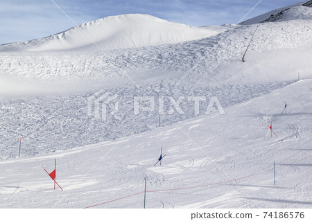 Trace for ski slalom with gates marked by flags, prepared by snowcat and off-piste slope Trace for ski slalom with gates marked by flags, prepared by snowcat and off-piste slope 74186576