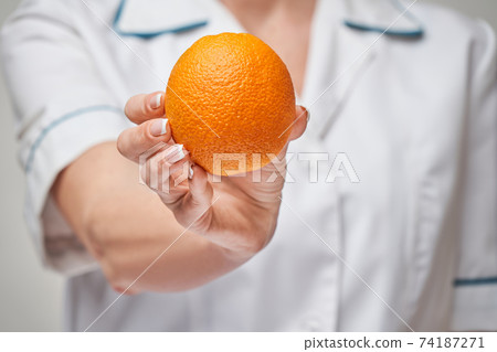 nutritionist doctor healthy lifestyle concept - holding fresh organic orange fruit 74187271