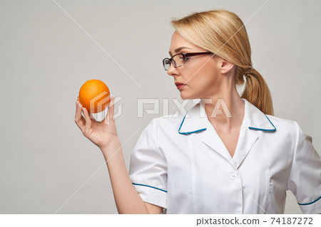 nutritionist doctor healthy lifestyle concept - holding fresh organic orange fruit 74187272