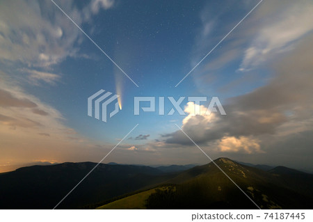 Summer night in mountains with starry dark blue cloudy sky and Neowise comet with light tail. Summer night in mountains with starry dark blue cloudy sky and Neowise comet with light tail. 74187445