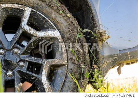 Close up of dirty off road car wheels with dirty tires covered with yellow mud. Close up of dirty off road car wheels with dirty tires covered with yellow mud. 74187461