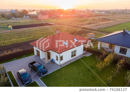 Aerial view of a private suburban house with parked cars in back yard. Aerial view of a private suburban house with parked cars in back yard. 74188137