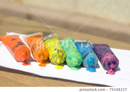 Top view of colorful watercolor paint in plastic tubes on white paper background, art and creativity concept. 74188157