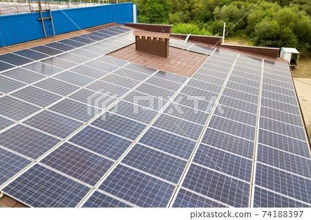 Aerial view of solar power plant with blue photovoltaic panels mounted of industrial building roof. 74188397