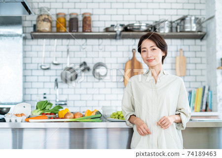 Middle-aged woman in the kitchen Middle-aged woman in the kitchen 74189463