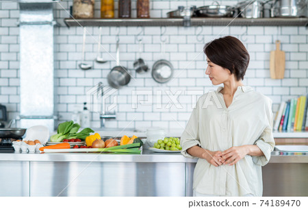 Middle-aged woman in the kitchen Middle-aged woman in the kitchen 74189470