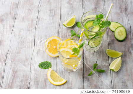 Glasses with fresh lemon, cucumber, lime and mint on white wooden background, copy space. Glasses with fresh lemon, cucumber, lime and mint on white wooden background, copy space. 74190689