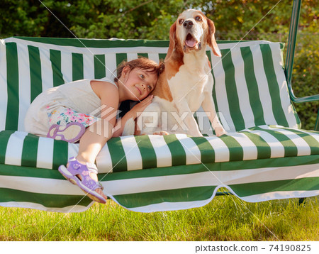 Happy little girl playing with dog in garden. Happy little girl playing with dog in garden. 74190825
