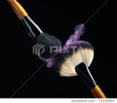Makeup concept with a professional makeup brushes with glowing purple eye shadow. Makeup concept with a professional makeup brushes with glowing purple eye shadow. 74190884