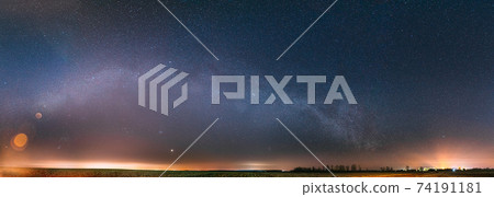Night Starry Sky With Glowing Stars Above Countryside Landscape. Milky Way Galaxy And Rural Field Meadow In Early Spring. Panorama, Panoramic View 74191181