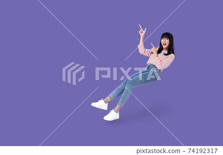 beautiful smiling asian girl hand pointing up to copy space isolated on purple background. beautiful smiling asian girl hand pointing up to copy space isolated on purple background. 74192317
