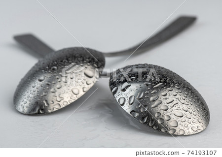 Artistic place setting photo of two spoons with water droplets. Artistic place setting photo of two spoons with water droplets. 74193107