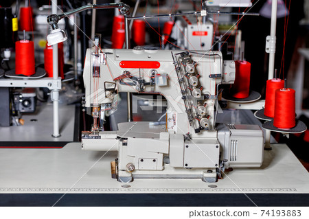 Modern sewing equipment, multifunctional sewing machine with spools of red thread close-up. Modern sewing equipment, multifunctional sewing machine with spools of red thread close-up. 74193883