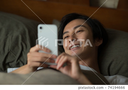 男人在床上看著智能手機 男人在床上看著智能手機 74194666