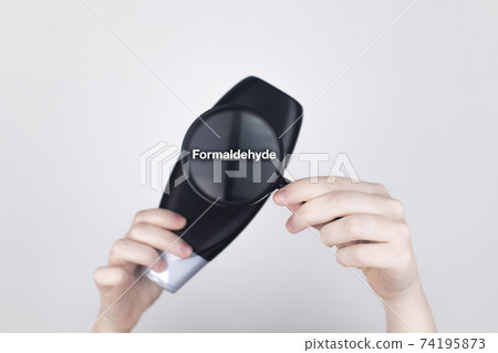 Chemical components on the shampoo label: Formaldehyde. Female hands hold a magnifying glass on the jar, which indicates the harmful ingredient. White background, place for your text 74195873