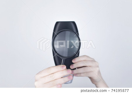 Chemical or natural components of the shampoo, ingredients and composition of the hair product. Female hands hold a black shampoo jar and a magnifying glass. Place for text Chemical or natural components of the shampoo, ingredients and composition of the hair product. Female hands hold a black shampoo jar and a magnifying glass. Place for text 74195877