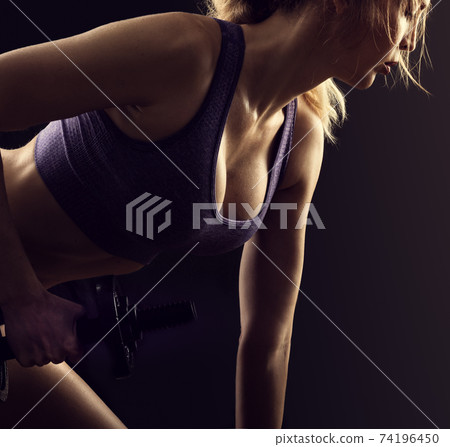 Slim athletic woman Holding dumbbell in the hand Slim athletic woman Holding dumbbell in the hand 74196450