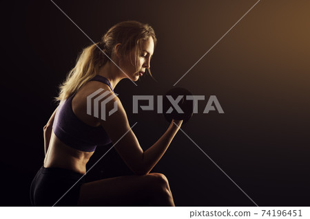 Slim athletic woman Holding dumbbell in the hand Slim athletic woman Holding dumbbell in the hand 74196451