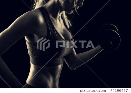 Slim athletic woman Holding dumbbell in the hand Slim athletic woman Holding dumbbell in the hand 74196457