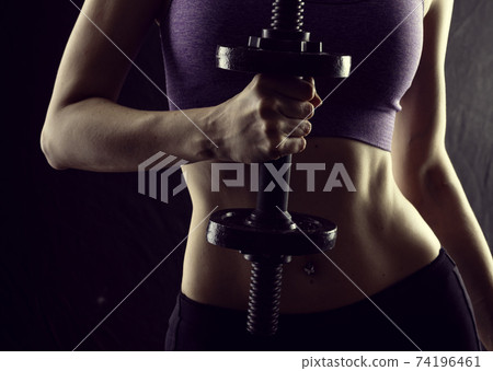 Slim athletic woman Holding dumbbell in the hand Slim athletic woman Holding dumbbell in the hand 74196461