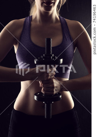Slim athletic woman Holding dumbbell in the hand Slim athletic woman Holding dumbbell in the hand 74196463