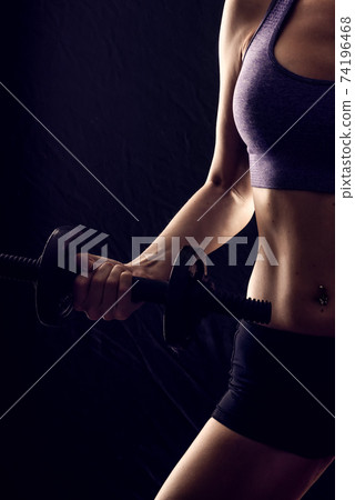 Slim athletic woman Holding dumbbell in the hand 74196468