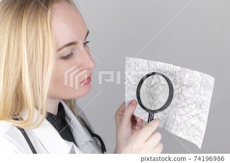 A neurologist with a magnifying glass examines an encephalogram of a patient brain. Schedule of electroencephalograms study of brain currents for signs of epilepsy and pathologies A neurologist with a magnifying glass examines an encephalogram of a patient brain. Schedule of electroencephalograms study of brain currents for signs of epilepsy and pathologies 74196986