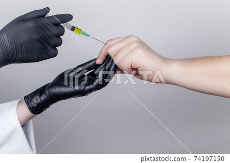An orthopedic surgeon gives an injection in the finger joint. Treatment of osteoarthritis with hormonal drugs or drugs based on hyaluronic acid. Help with diseases that damage the cartilage of the An orthopedic surgeon gives an injection in the finger joint. Treatment of osteoarthritis with hormonal drugs or drugs based on hyaluronic acid. Help with diseases that damage the cartilage of the 74197150